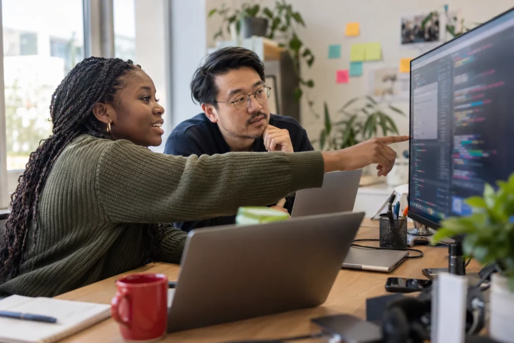 Two software developers pair programming at a shared desk