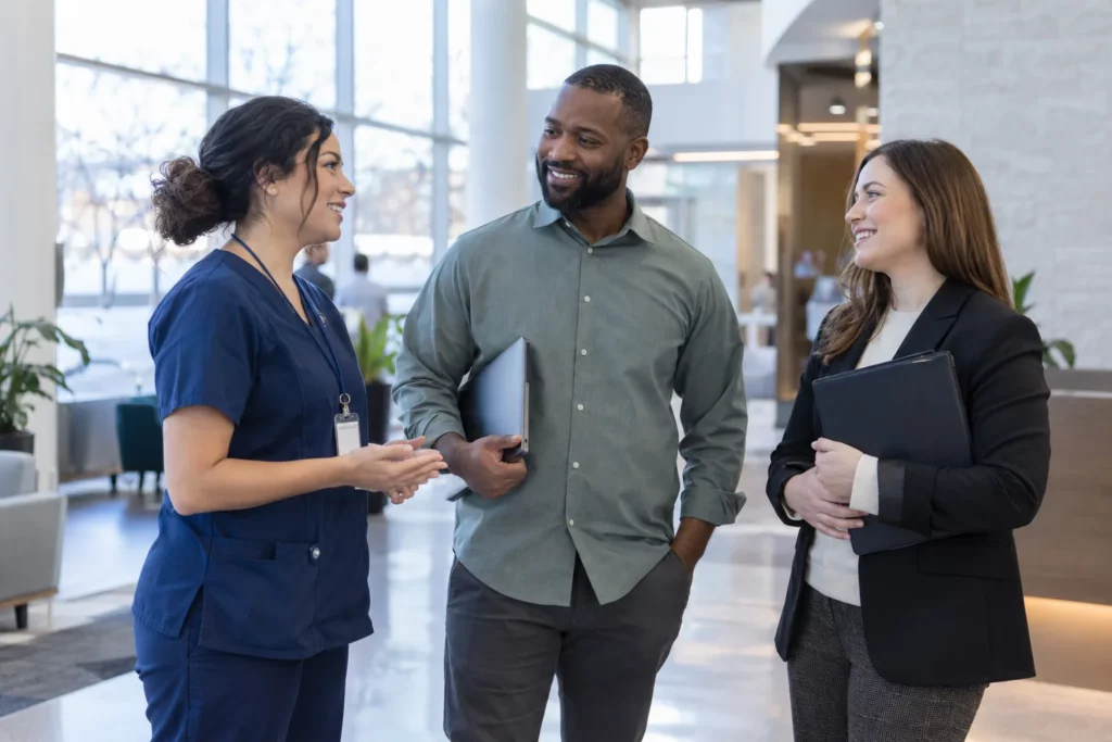 Three professionals from healthcare, technology and business talking in an office lobby