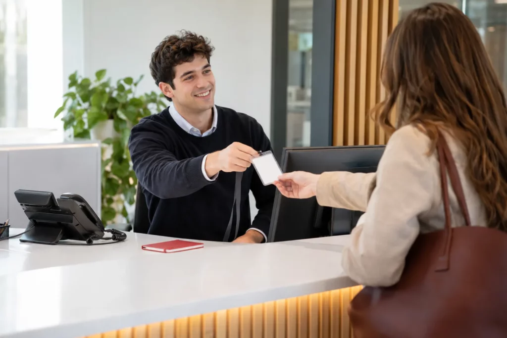 An office coordinator greeting a visitor at a front office reception desk